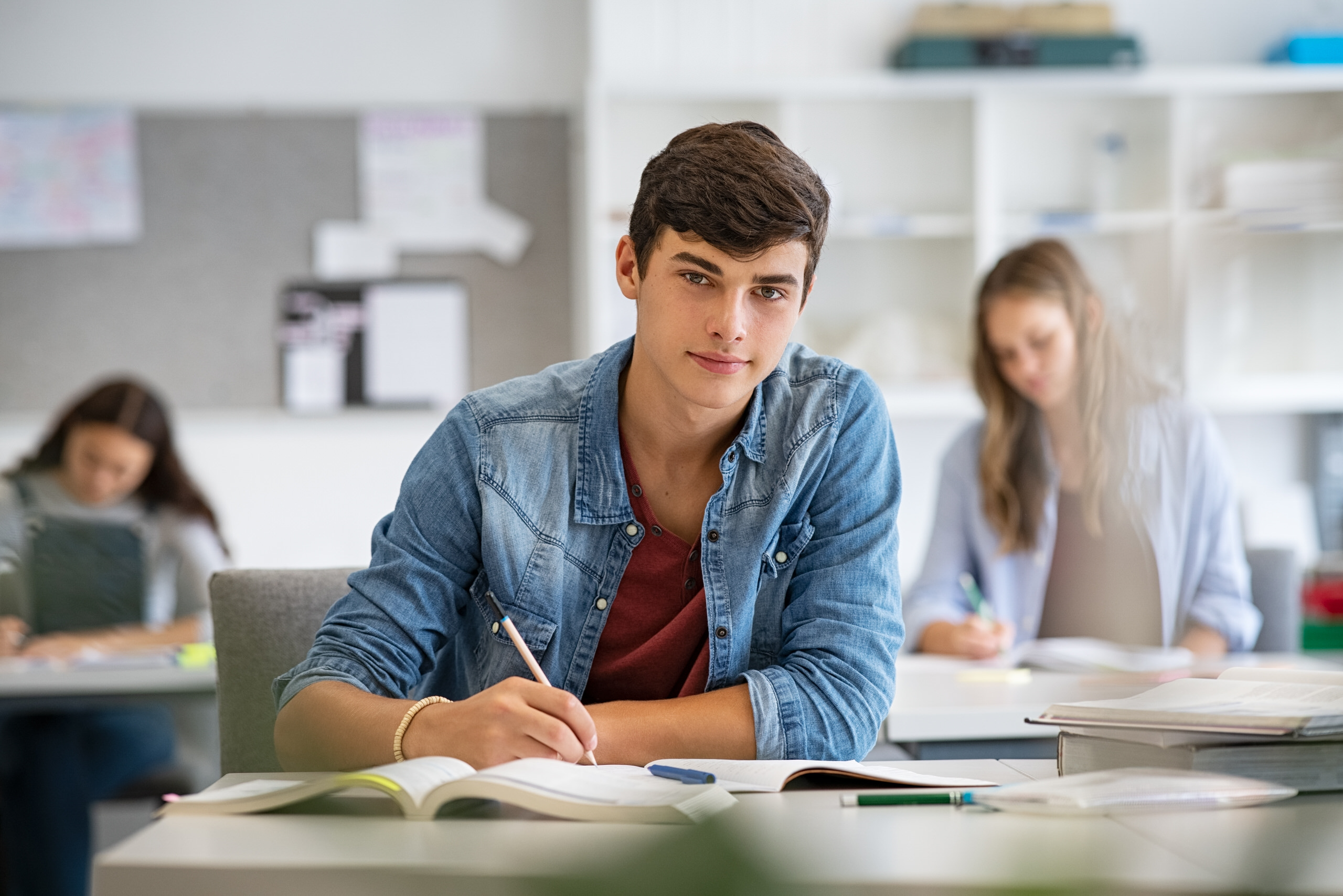 Étudiant concentré prenant des notes en consultant des livres dans une bibliothèque universitaire